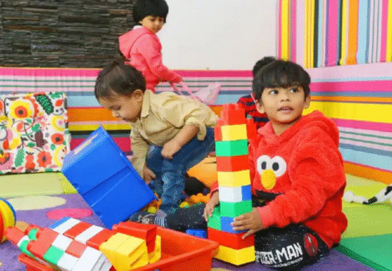 Teacher kneeling to help a child with a puzzle, smiling warmly.